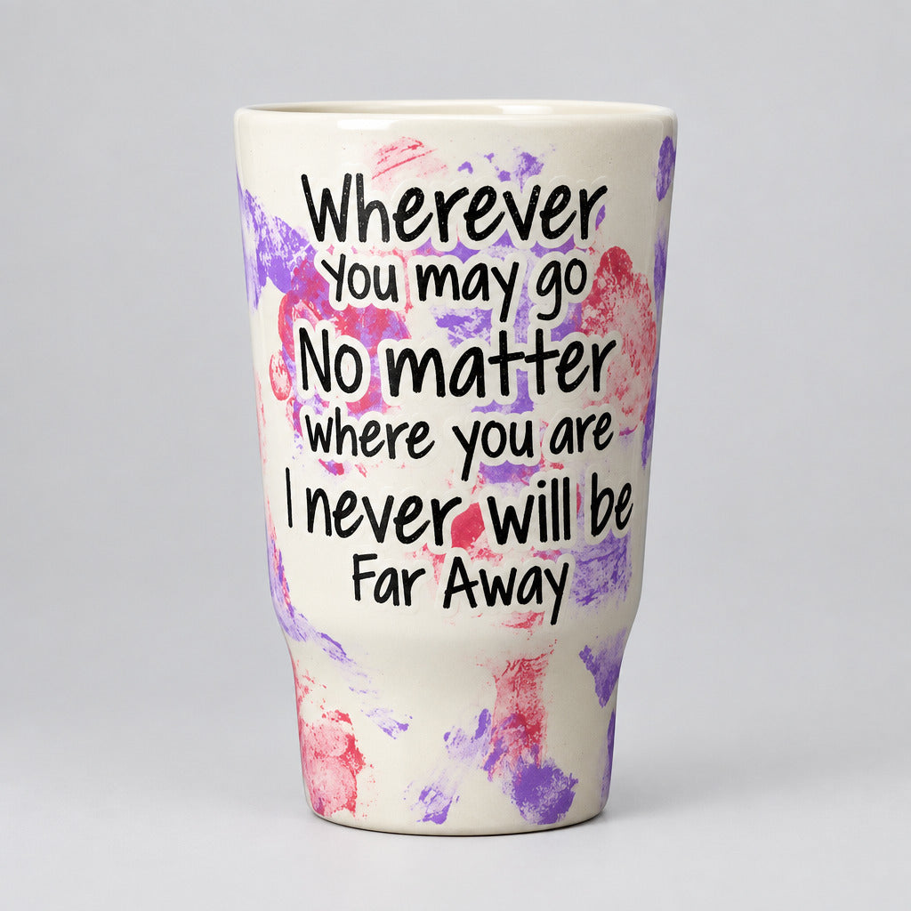 A white insulated tumbler with a purple and pink paint-splatter pattern, featuring the inspirational quote 'Wherever You may go No matter where you are I never will be Far Away' in black handwritten-style lettering.