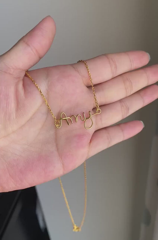 Hand holding wire name pendant